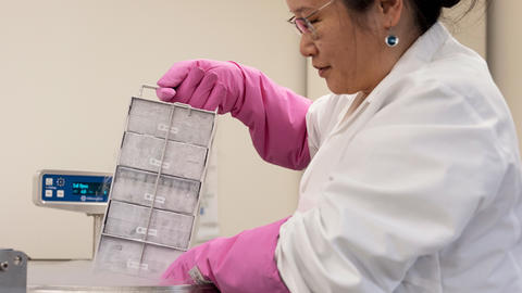 a person removing a tray from a cryogenic vat