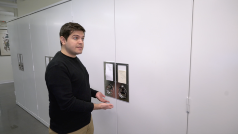 a person standing in front of white metal cabinets