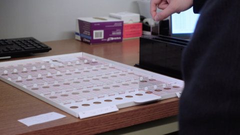 a tray of glass slides and one slide being placed in a scanning tray