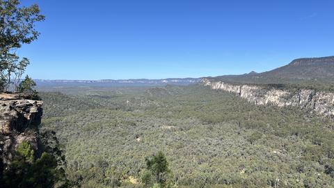 a wide green valley with cliffs on each side