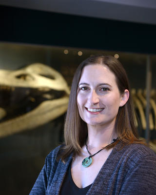 a person standing in front of a kronosaurus skeleton in a museum