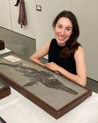 a person seated with a fossil specimen 