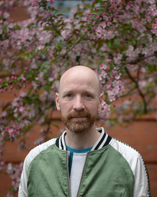 a person standing outside, in front of a blooming cherry tree