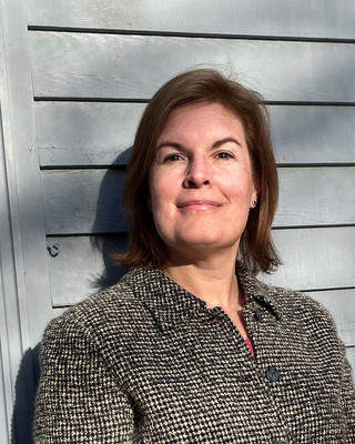 a person standing against grey siding