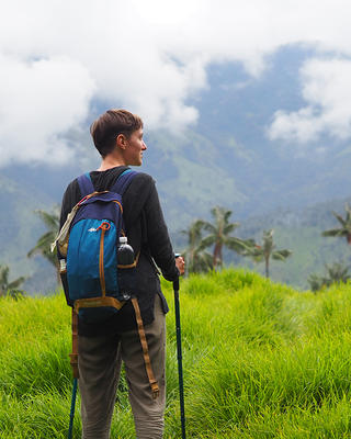 a person sanding in tall green grass in a cloud forest