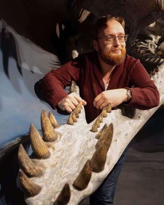 a person standing behind a large fossil lower jaw