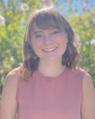 a person smiling at the camera, standing outside