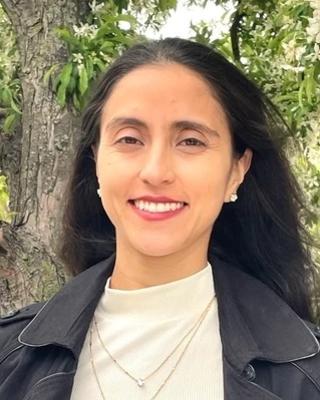 a person smiling at the camera, with trees in the background