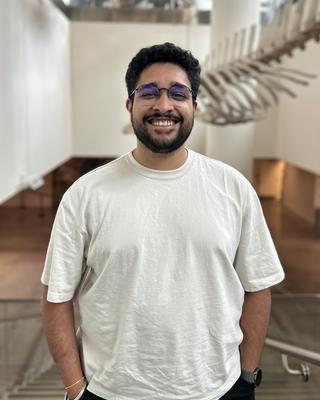 a person smiling at the camera, indoors with a dolphin in the background