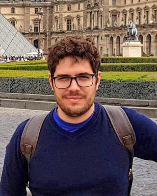a person looking at the camera, in front of the Louvre