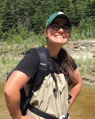 a person on the banks of a river, smiling at the camera