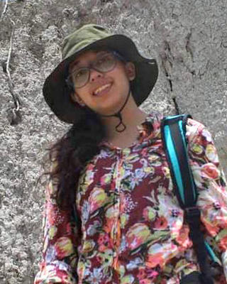 a person outside, with a cliff behind them.
