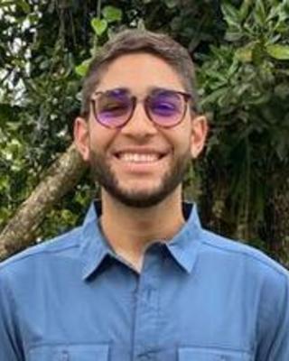 a person smiling at the camera with foliage behind them