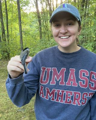 a person standing outside, with a small bird perched on their finger
