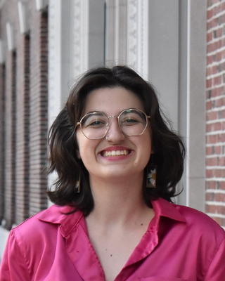 a person in front of a building, smiling at the camera