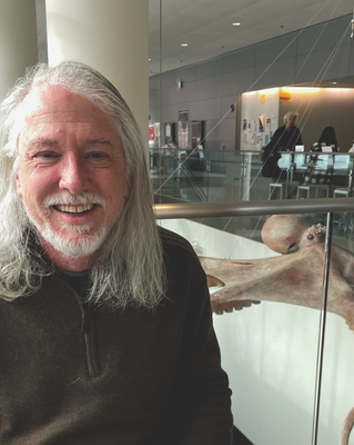 a person smiling at the camera, with a octopus model in the background