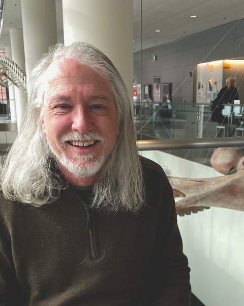 a person smiling at the camera, with a octopus model in the background