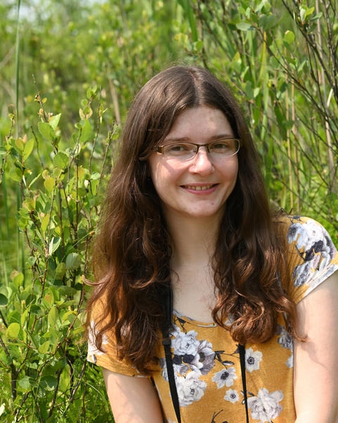 a person outside, in front of green foliage