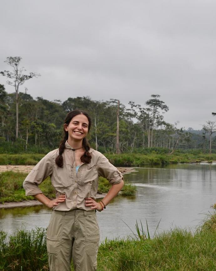 a person standing in front of a river and green foliage