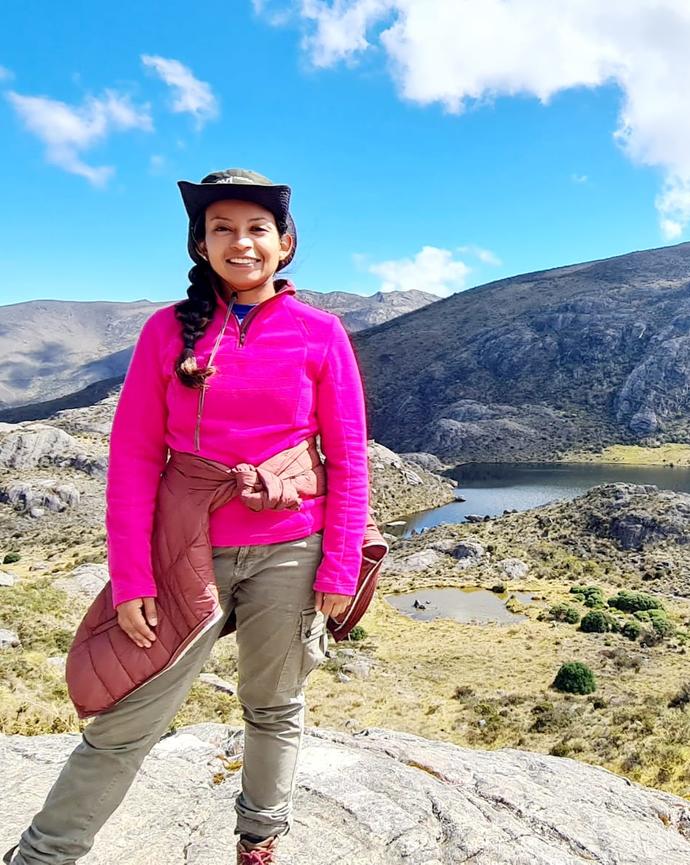 a person standing outside with a valley, stream and mountain background