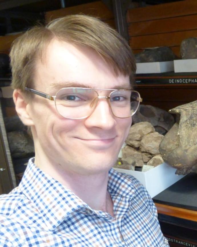 a person standing next to a fossil skull