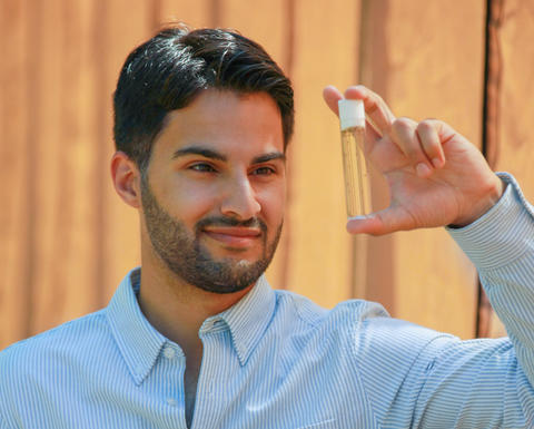 a person holding up and looking at a glass tube